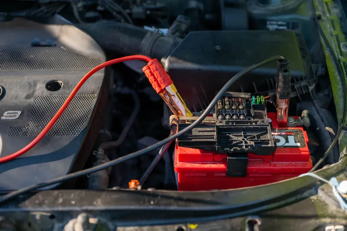Booster cables connected to a battery in an engine bay