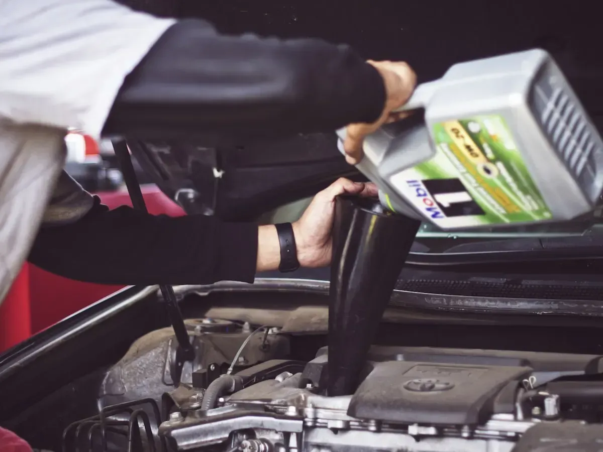 A mechanic topping up engine oil